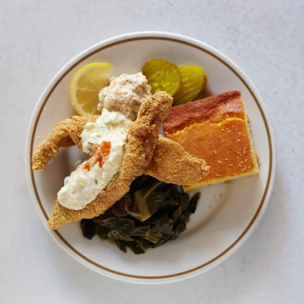 Southern fried catfish with tartar sauce, collard greens, cornbread, coleslaw, lemon, and pickles.