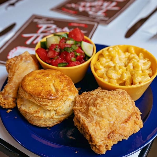 Fried chicken, biscuits, mac and cheese, and watermelon salad on a blue plate.