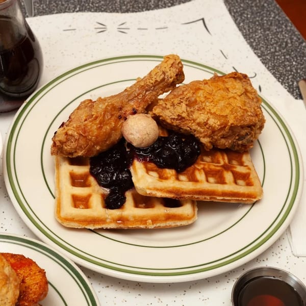 Pies 'n' Thighs' fried chicken and waffles with blueberry compote and a pat of butter.