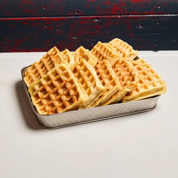 A metal tray filled with golden-brown waffles, ready to be served at Pies 'n' Thighs.